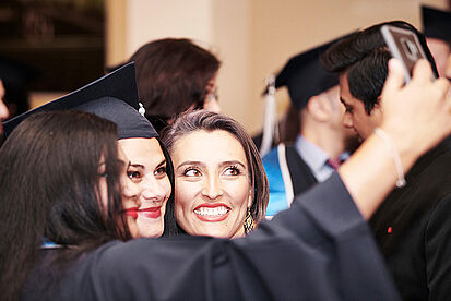 Three MBA students take a selfie at the graduation