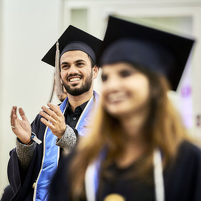 two graduate applauding during graduation ceremony