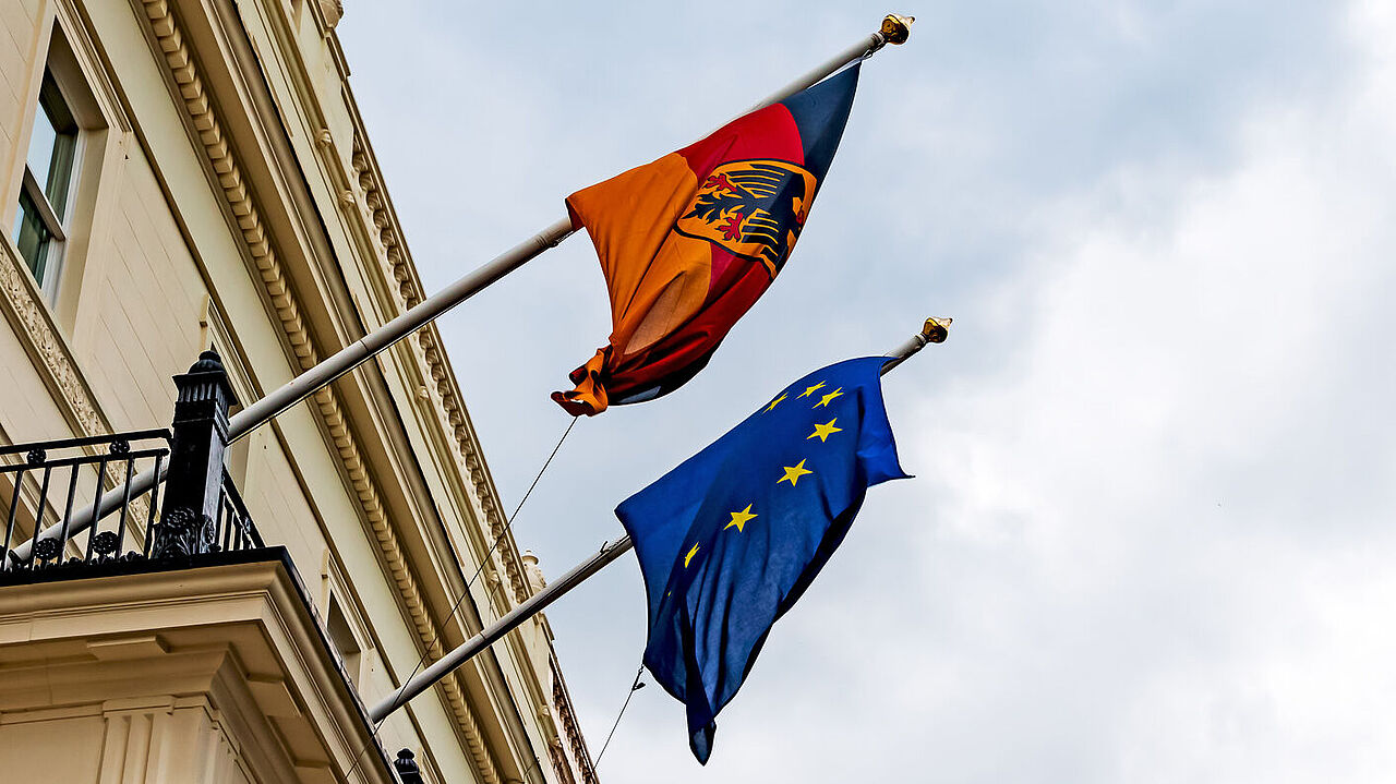 Die deutsche und die EU-Flagge hängen an einem Gebäude