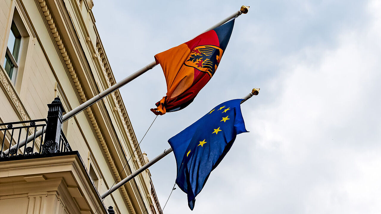 German and European flag hanging from a building