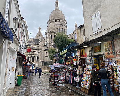 A small alley with tourist shops, in the back ground you can see Montmatre
