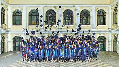Absolvent:innen des IGC werfen ihre Hüte auf der Abschlussfeier