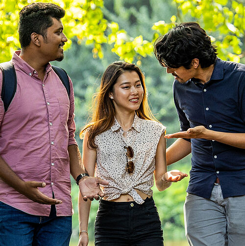 three students talking and walking in a park
