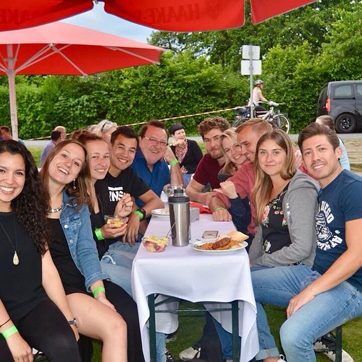 Eine Gruppe von Studierenden, die gemeinsam draußen im Biergarten sitzen