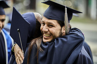 Two students in gowns hugging on graduation