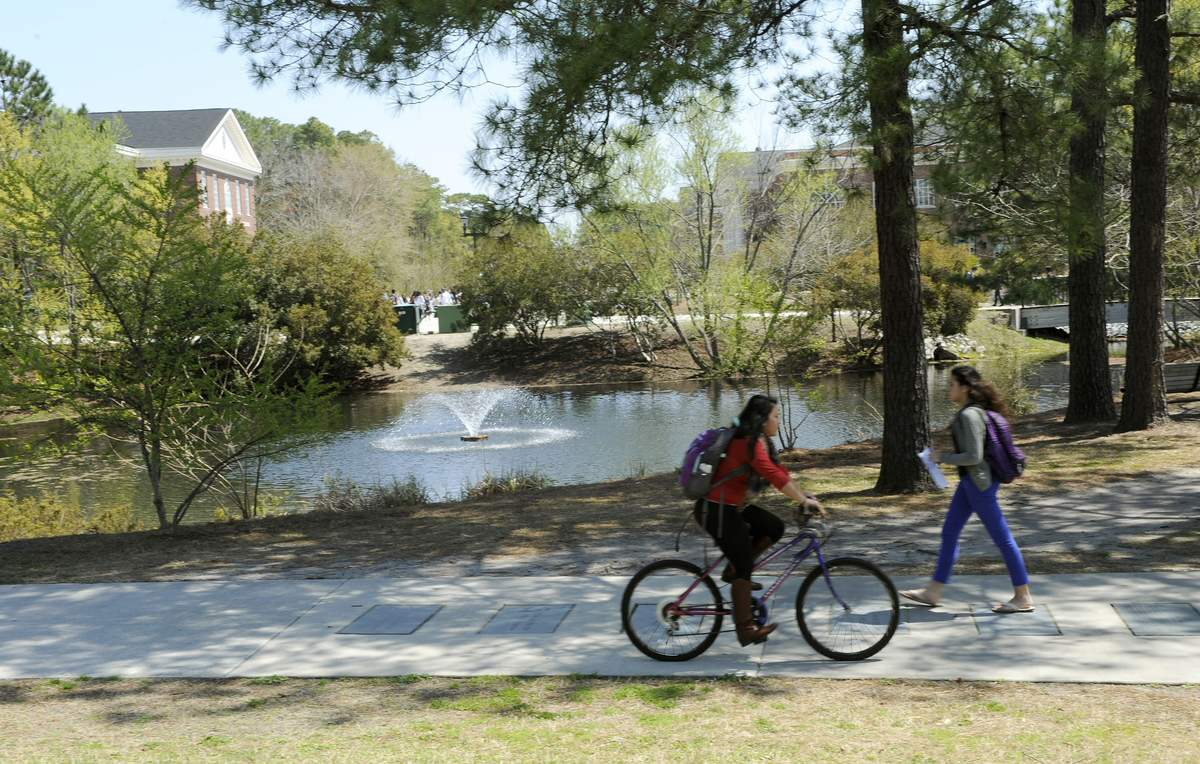 der parkähnliche Campus von UNCW, ein Fahrrad kommt einer Fußgängerin entgegen