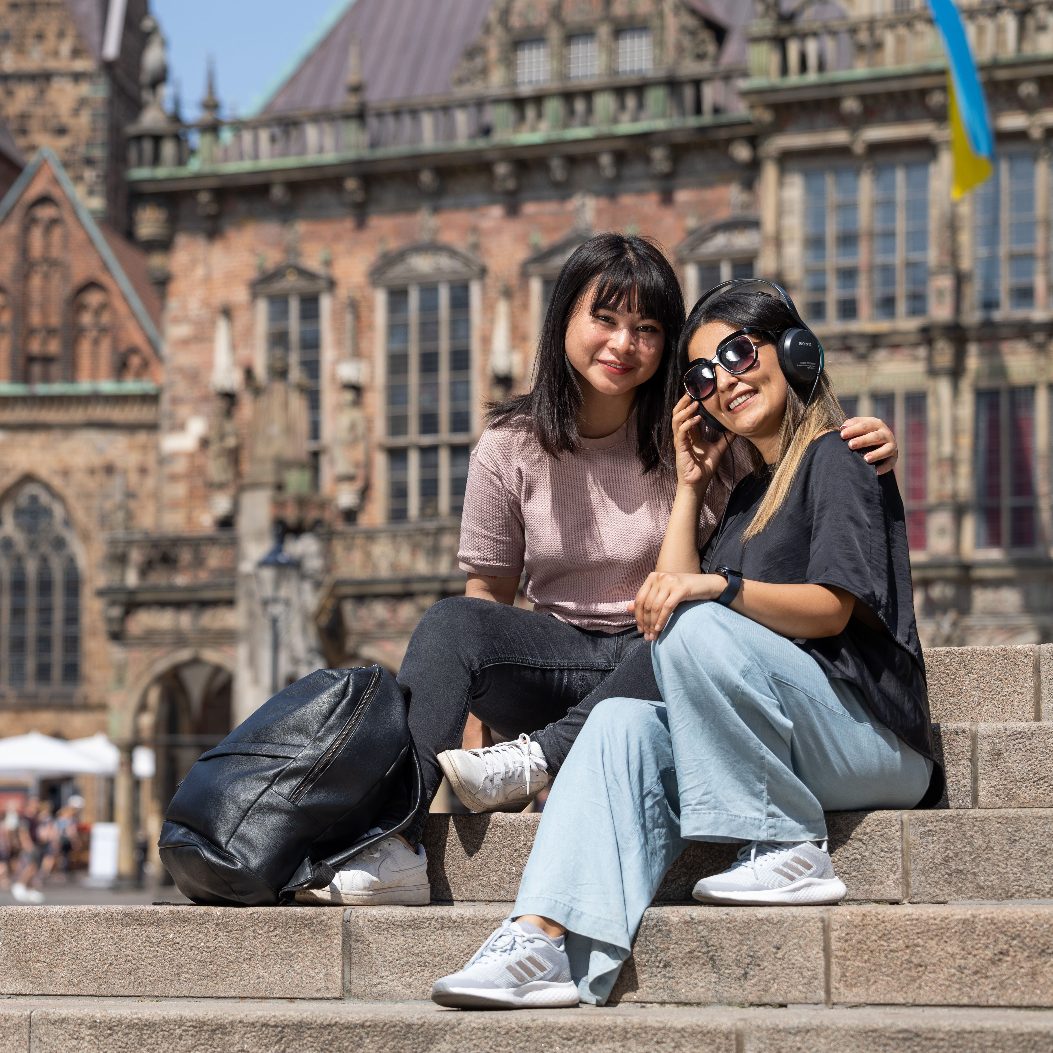 Zwei Studentinnen sitzen auf den Treppen der Bremischen Bürgerschaft, im Hintergund ist das Ratshaus